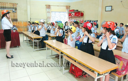 Giáo viên Trường Tiểu học Nguyễn Trãi (thành phố Yên Bái) hướng dẫn học sinh cách đội mũ bảo hiểm.

