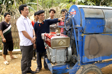 Bí thư Bàn Văn Lương (áo đen) giới thiệu với lãnh đạo xã chiếc máy tuốt lúa anh vừa đầu tư để phục vụ bà con trong thôn.