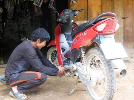 Nông dân huyện Mù Cang Chải sau khi học nghề sửa chữa xe máy đã mở hiệu sửa chữa tại nhà. (Ảnh: Thu Hạnh)