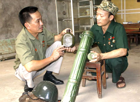 Cựu chiến binh Nguyễn Văn Kim (bên phải) cùng đồng đội là cựu chiến binh Lê Huy Tâm ôn lại kỷ niệm bên các kỷ vật một thời.