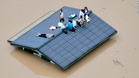 Người dân trèo lên mái nhà chờ được giải cứu.
