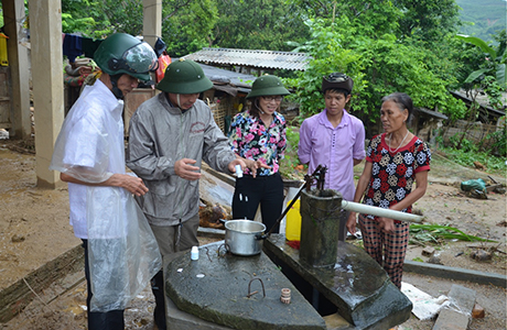 Lãnh đạo Sở Y tế hướng dẫn người dân xã Sơn Lương, huyện Văn Chấn vệ sinh khử khuẩn nguồn nước sinh hoạt.
