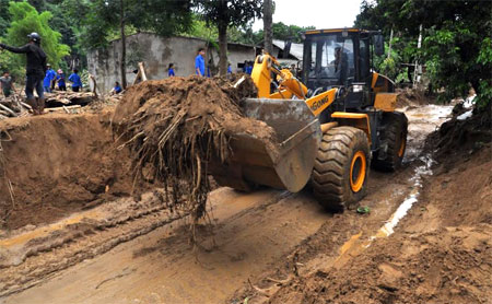 Các lực lượng đang khẩn trương san, hót, gạt bùn đất để khôi phục giao thông tuyến đường đi xã Nậm Mười, huyện Văn Chấn.