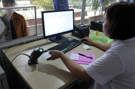 Cán bộ tại Bộ phận tiếp đón bệnh nhân Trung tâm Y tế huyện Trấn Yên quét mã thẻ BHYT cho bệnh nhân.