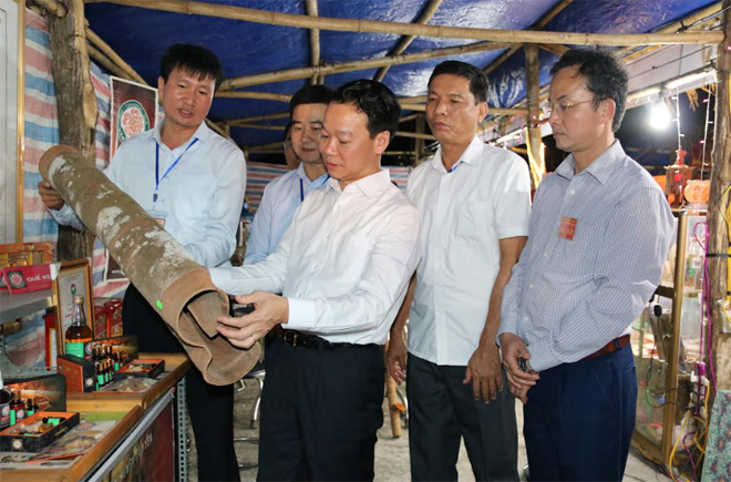 Đồng chí Đỗ Đức Duy - Phó Bí thư Tỉnh ủy, Chủ tịch UBND tỉnh trao đổi với lãnh đạo huyện Văn Yên về chất lượng sản phẩm quế vỏ được trưng bày tại Lễ hội đền Đông Cuông.