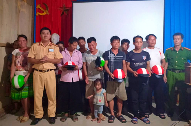 Cán bộ Đội Cảnh sát giao thông trật tự, Công an huyện Trấn Yên trao mũ bảo hiểm cho các hộ nghèo thôn Khe Tiến, xã Hồng Ca.