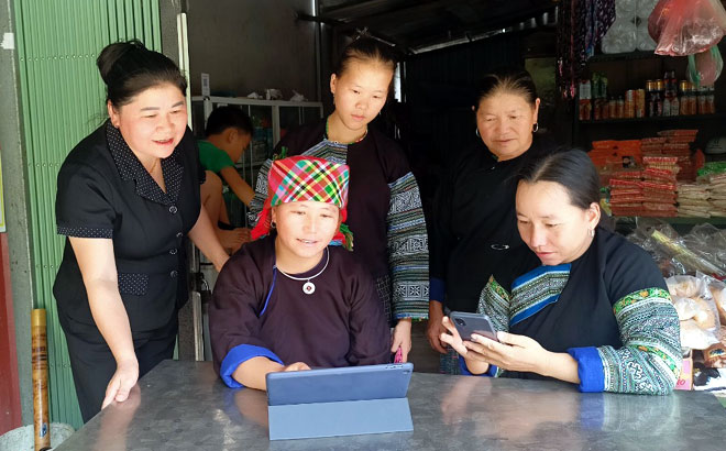 Chị Sùng Thị Mỷ - Chủ tịch Hội LHPN huyện Mù Cang Chải (người mặc áo đen, ngoài cùng bên trái) đang giới thiệu các ứng dụng CNTT cho hội viên phụ nữ bản Khao Mang, xã Khao Mang.