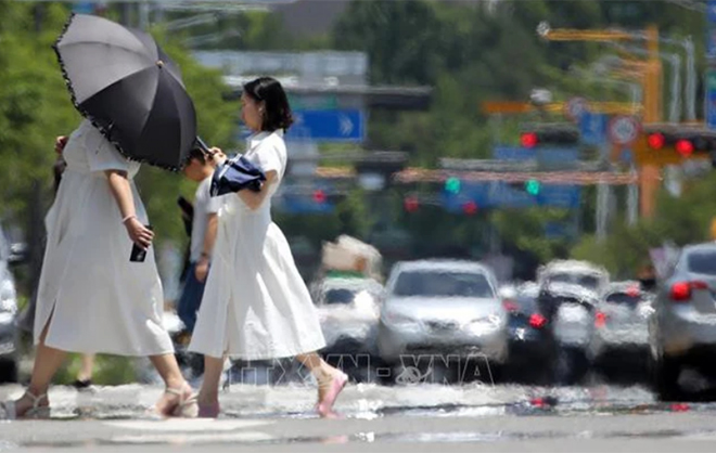 Người dân che ô tránh nắng khi di chuyển trên đường phố ở Gwangju, Hàn Quốc, ngày 15/6/2023.