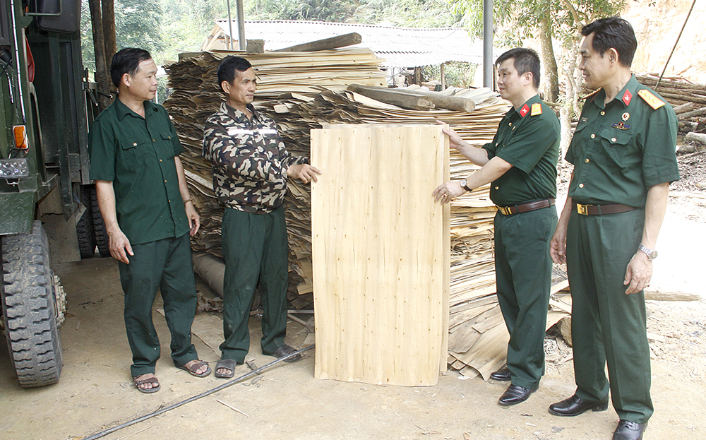 Cựu chiến binh Hoàng Xuân Hưởng (thứ 2, bên trái) giới thiệu quy trình sản xuất ván bóc với lãnh đạo Hội Cựu chiến binh huyện Yên Bình.