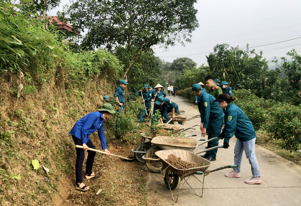 Lực lượng dân quân xã Đại Minh, huyện Yên Bình giúp dân làm sạch môi trường trong Phong trào “Ngày cuối tuần cùng dân”.
