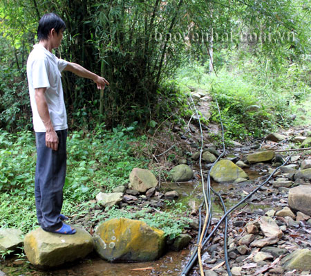 Một người dân chỉ cho phóng viên hệ thống ống dẫn nước từ núi Yến về thôn Đá Trắng.