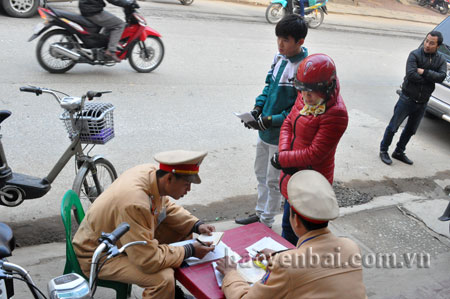 Cảnh sát giao thông thành phố Yên Bái lập biên bản xử lý học sinh đi xe đạp điện không đội mũ bảo hiểm.
