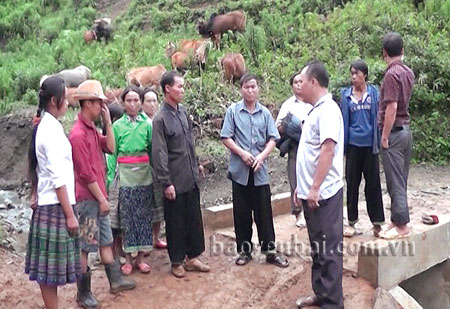 Ông Thào A Tủa (áo đen, trái sang) trao đổi với người dân trong thôn Suối Giao, xã Xà Hồ, huyện Trạm Tấu về cách chăn nuôi gia súc.
