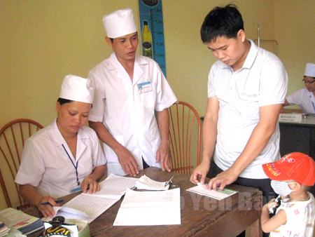Cán bộ Trạm Y tế phường Yên Thịnh đón tiếp, làm thủ tục tiêm phòng cho trẻ.