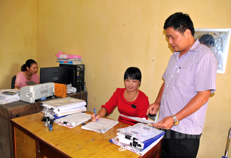 Chủ tịch UBND xã Tân Thịnh - Nguyễn Văn Tĩnh (người đứng) trao đổi với cán bộ kế toán xã.
