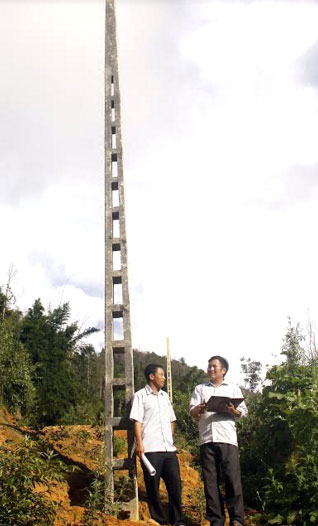 Bí thư Chi bộ Hảng Tồng Chư (bên phải) trao đổi với lãnh đạo xã về việc vận động bà con hiến đất xây dựng đường điện lưới quốc gia.