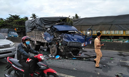 Hiện trường vụ tai nạn khiến tài xế xe tải và phụ xe bị thương nặng kẹt trong cabin bẹp dúm.