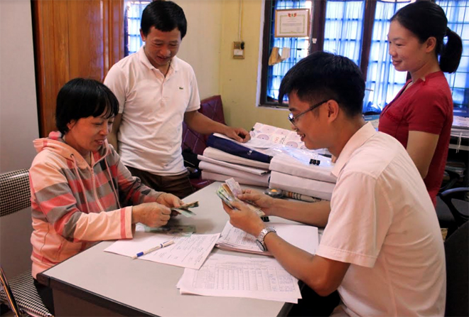 Bà Trần Thị Châm (người ngồi, bên trái) ở thôn Hồng Sơn, xã Sơn Thịnh nhận tiền hỗ trợ tại Phòng Nông nghiệp và Phát triển nông thôn huyện Văn Chấn.
