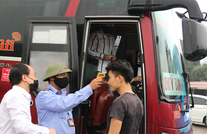 Ban Quản lý Bến xe khách Yên Bái đo thân nhiệt và phát khẩu trang cho hành khách.