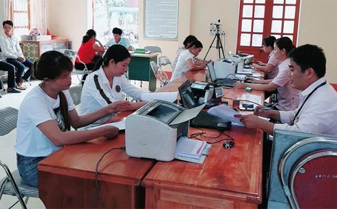 Cán bộ tín dụng Phòng Giao dịch NHCSXH huyện Văn Yên làm thủ tục giải ngân tại một điểm giao dịch xã.