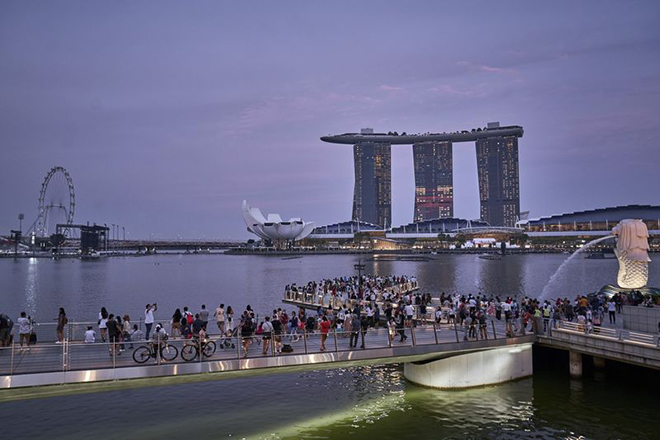 Khách tham quan tượng Merlion và khách sạn Marina Bay Sands ở Singapore.