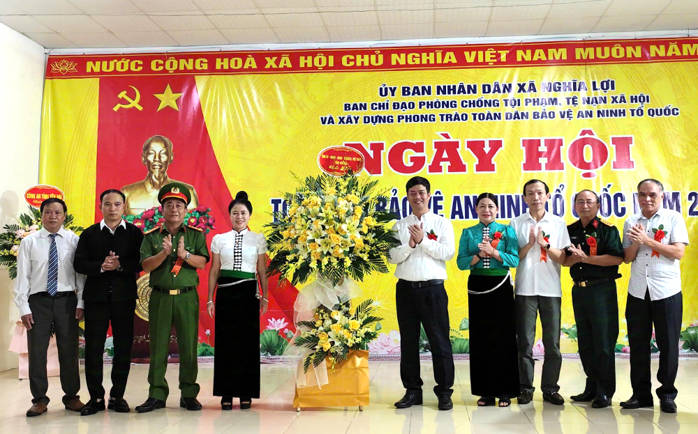 Các đồng chí Nguyễn Minh Toàn -  Chủ nhiệm Ủy ban Kiểm tra Tỉnh ủy, Hoàng Thị Vĩnh - Trưởng ban Dân vận Tỉnh ủy tặng hoa chúc mừng xã Nghĩa Lợi nhân Ngày hội “Toàn dân Bảo vệ an ninh Tổ quốc”.