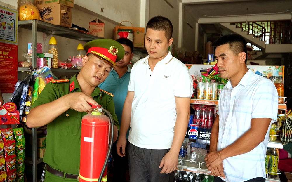 Công an phường Hợp Minh hướng dẫn người dân sử dụng bình chữa cháy tại gia đình trong mô hình “Tổ liên gia an toàn về phòng cháy, chữa cháy”.