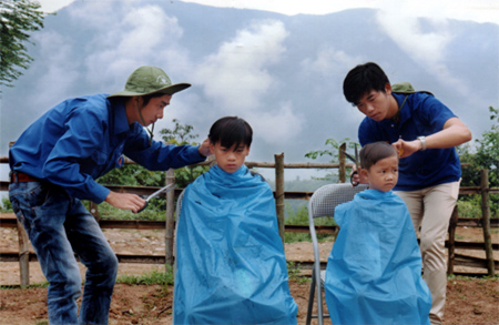 Thanh niên tình nguyện cắt tóc cho các em nhỏ xã Pá Lau (Trạm Tấu).
(Ảnh: Thanh Miền)
