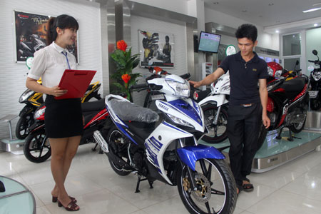 Nhân viên bán hàng Công ty TNHH Hòa Bình tư vấn cho khách hàng mua xe máy.
