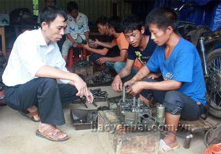 Thầy Trần Quốc Bình (bên trái) đang hướng dẫn học viên lớp sửa chữa xe máy.
