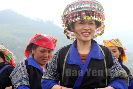 Chị Lý Thị Chơ (bên trái) giúp khách du lịch mặc trang phục truyền thống của người dân tộc Mông.