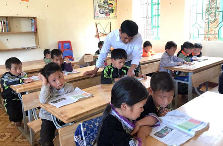 Thầy giáo Bùi Công Nguyên - một trong những điển hình tiên tiến học tập và làm theo Bác ở huyện Mù Cang Chải đang hướng dẫn học sinh tập đọc.