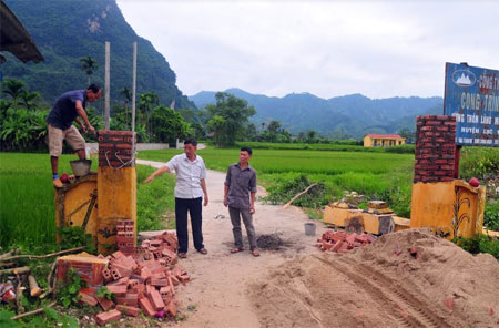 Người dân thôn Làng Mường sửa sang lại cổng làng văn hóa.