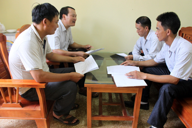 Cán bộ Trung tâm Dịch vụ hỗ trợ và Phát triển nông nghiệp huyện Trạm Tấu (bên trái) trao đổi về phòng chống bệnh dịch tả lợn châu Phi với lãnh đạo xã Trạm Tấu.