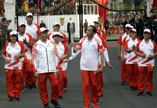 Tổng thống Indonesia Joko Widodo (giữa) cầm ngọn đuốc Thế vận hội châu Á và Bộ trưởng Thanh niên và Thể thao Imam Nahrawi (trái) trong buổi lễ Ngày Độc lập tại Cung điện Merdeka ở Jakarta, ngày 17/8/2018.