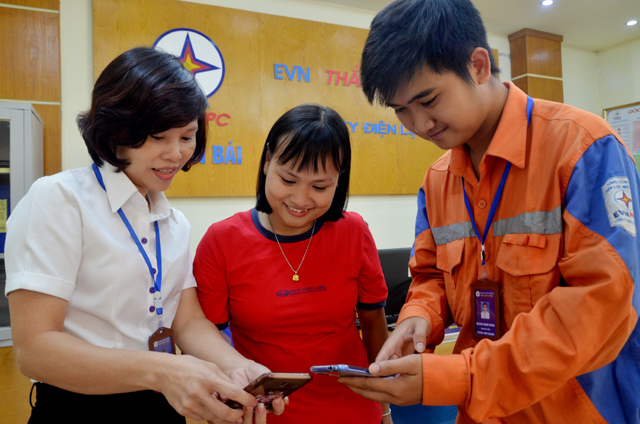 Cán bộ Công ty Điện lực Yên Bái hướng dẫn khách hàng các phương thức thanh toán tiền điện không dùng tiền mặt.