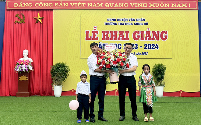 Đồng chí Bùi Minh Đức - Phó Tổng Biên tập Báo Yên Bái tặng hoa chúc mừng thầy, trò Trường Tiểu học và Trung học cơ sở Sùng Đô.