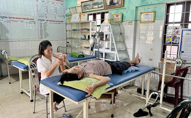 Nhân viên y tế chăm sóc sức khỏe cho người dân tại một trạm y tế ở tuyến xã.