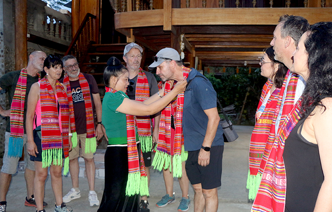 Du khách nước ngoài thích thú khi được khoác lên trang phục khăn piêu của người dân tộc Thái Mường Lò, Nghĩa Lộ.