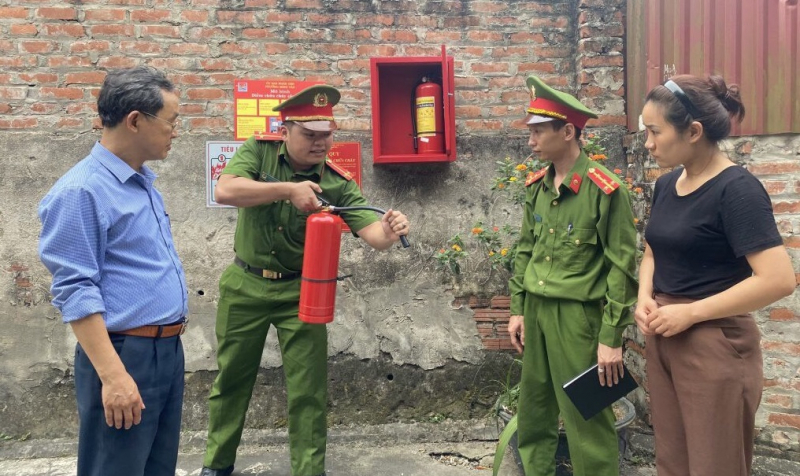 Cán bộ Công an phường Minh Tân hướng dẫn người dân sử dụng bình chữa cháy đúng quy định.
