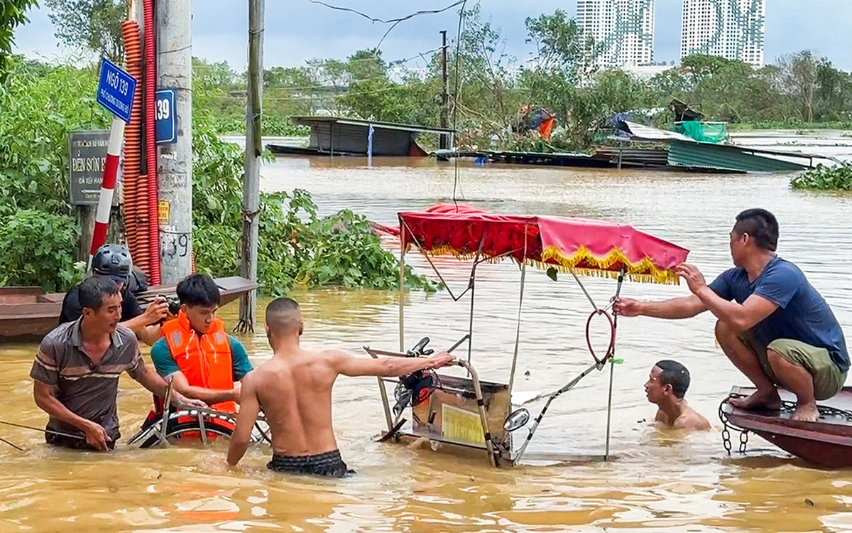 Người Hà Nội bơi xuống trong nước lũ ở sông Hồng để vớt tài sản.