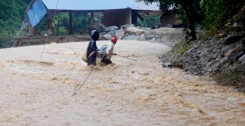 Người dân xã Hồ Bốn, huyện Mù Cang Chải cố gắng vượt qua dòng nước lũ để di chuyển đến nơi an toàn trong trận lũ lịch sử ngày 5/8/2023. (Ảnh: TTXVN)