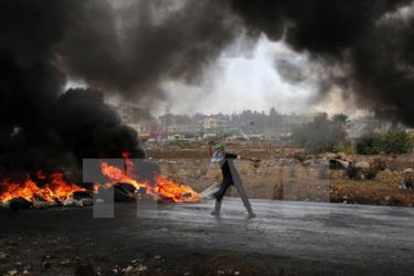 Thanh niên Palestine ném đá trong cuộc đụng độ với lực lượng an ninh Israel tại Al-Bireh, Bờ Tây ngày 26/10.