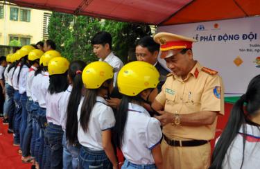 Các đồng chí lãnh đạo Văn phòng Ủy ban ATGT quốc gia, Quỹ AIP, nhà tài trợ và Ban ATGT tỉnh hướng dẫn học sinh đội mũ bảo hiểm đúng cách.