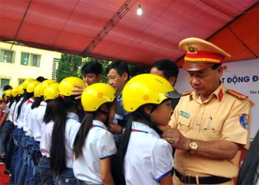 Lãnh đạo các cơ quan, ban, ngành hướng dẫn học sinh đội mũ bảo hiểm đúng cách.