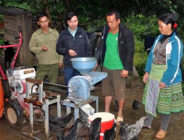 Vợ chồng anh Mùa A Dơ (đứng bên phải) giới thiệu chiếc máy nghiền ngô làm thức ăn cho gia súc.