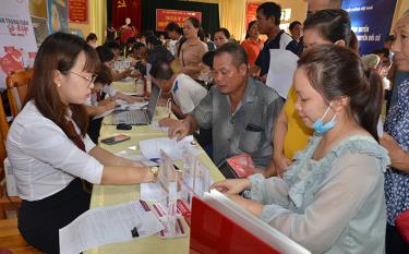 Nhân viên Ngân hàng Nông nghiệp và Phát triển nông thôn huyện Văn Yên hỗ trợ làm thẻ ngân hàng cho người dân.