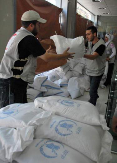 Nhân viên Chữ thập Đỏ Syria phân phát lương thực cho người dân Syria đi lánh nạn.
