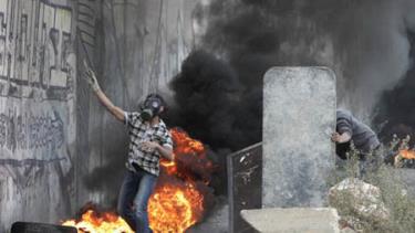 Một thanh niên Palestine giấu mặt sau hàng rào tự tạo trong cuộc xung đột với các binh sĩ Israel ngày 17/11.