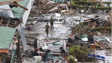 Binh sĩ Philippines đi bộ bên ngoài đống đổ nát ở sân bay Tacloban khi bão Haiyan tràn qua
